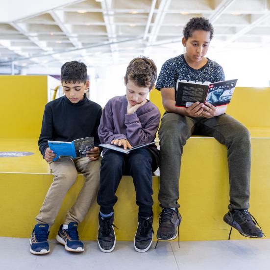 Tre drenge sidder på biblioteket og læser i hver sin bog
