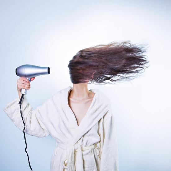 Kvinde der tørrer hår med en hårtørrer