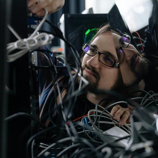 Fotografi af IT-supporter der roder med kabler bag computer