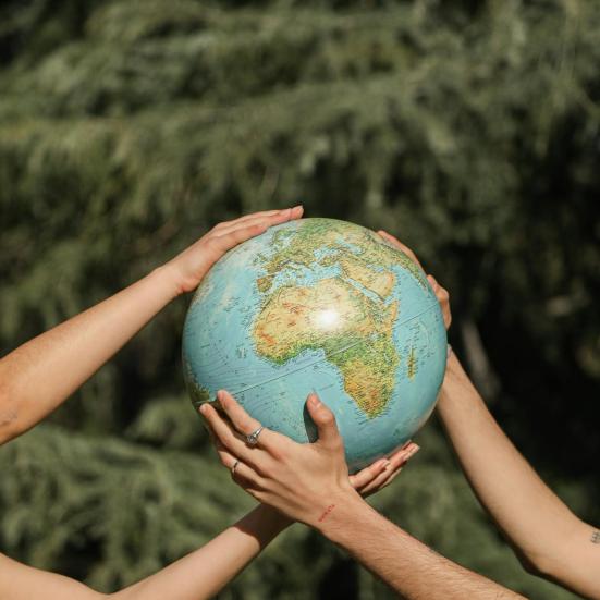 To personer holder en jordklode i armene imellem sig