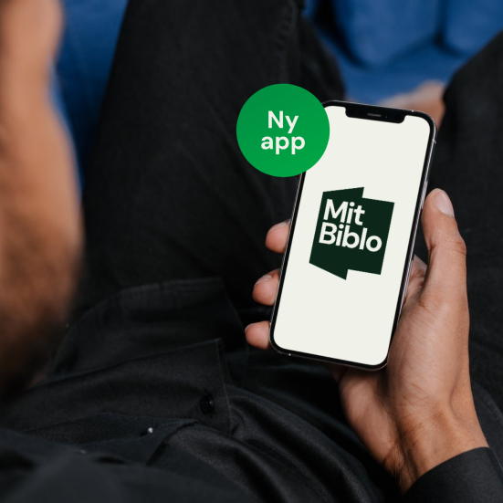 Sløret ansigt  set skråt bagfra, hånd med telefon i fokus, på skærmen "Mit Biblo"-logo. Grøn sticker med teksten "Ny app"