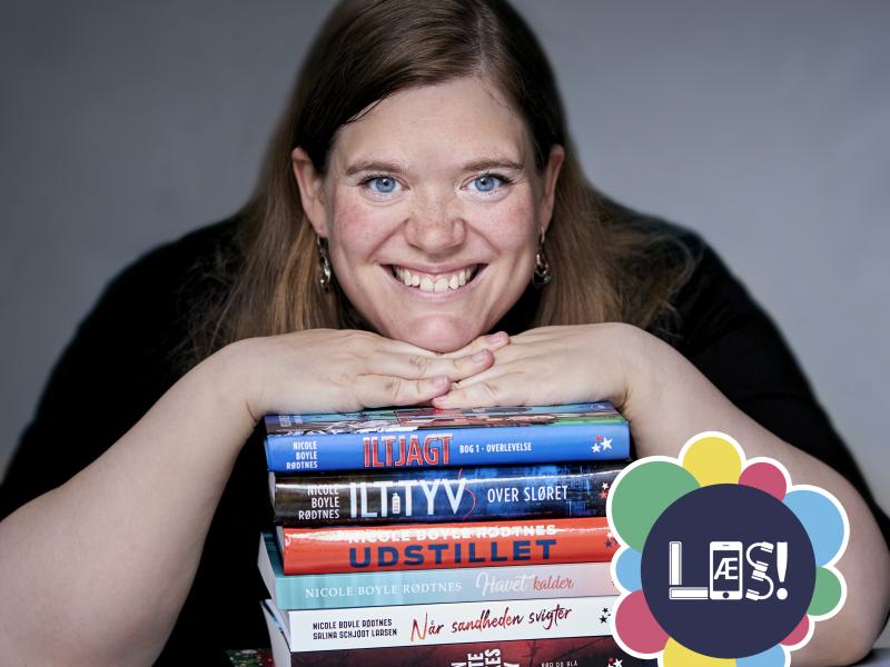 Portræt af Nicole Boyle Rødtnes med en stak af sine bøger
