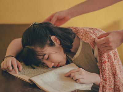 Tæppe lægges om skuldrene på sovende, ung kvinde