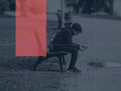 Foto af ung mand der sidder på en bænk ag stirrer på en smartphone