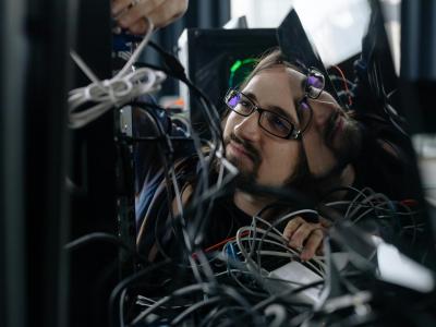 Fotografi af IT-supporter der roder med kabler bag computer