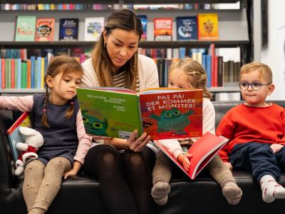 Foto af bibliotekar med billedbog og børn omkring