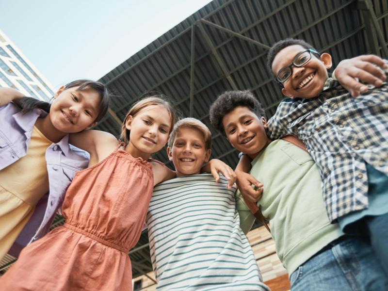 Smilende børn, der står med armene om hinandens skuldre