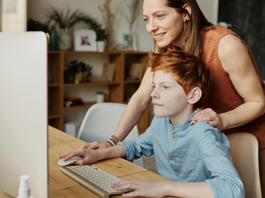 Barn får hjælp af sin mor til arbejde på computer